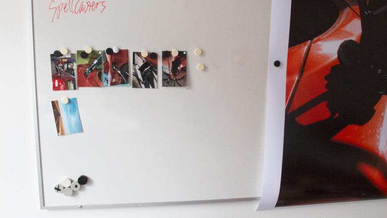 Analogfotos og storformatprint hængt op på whiteboard i værksted